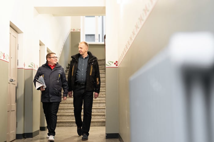 kaksi miestä kävelee rapukäytävässä patterin ohi.