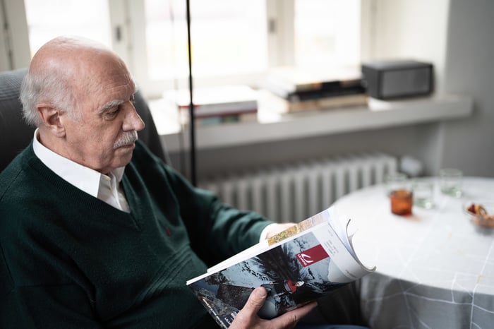 Vanha herra lukee kotona aikakauslehteä